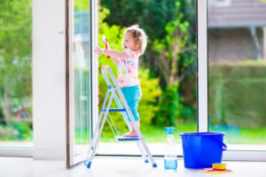 A girl cleaning large windows with soap and water
