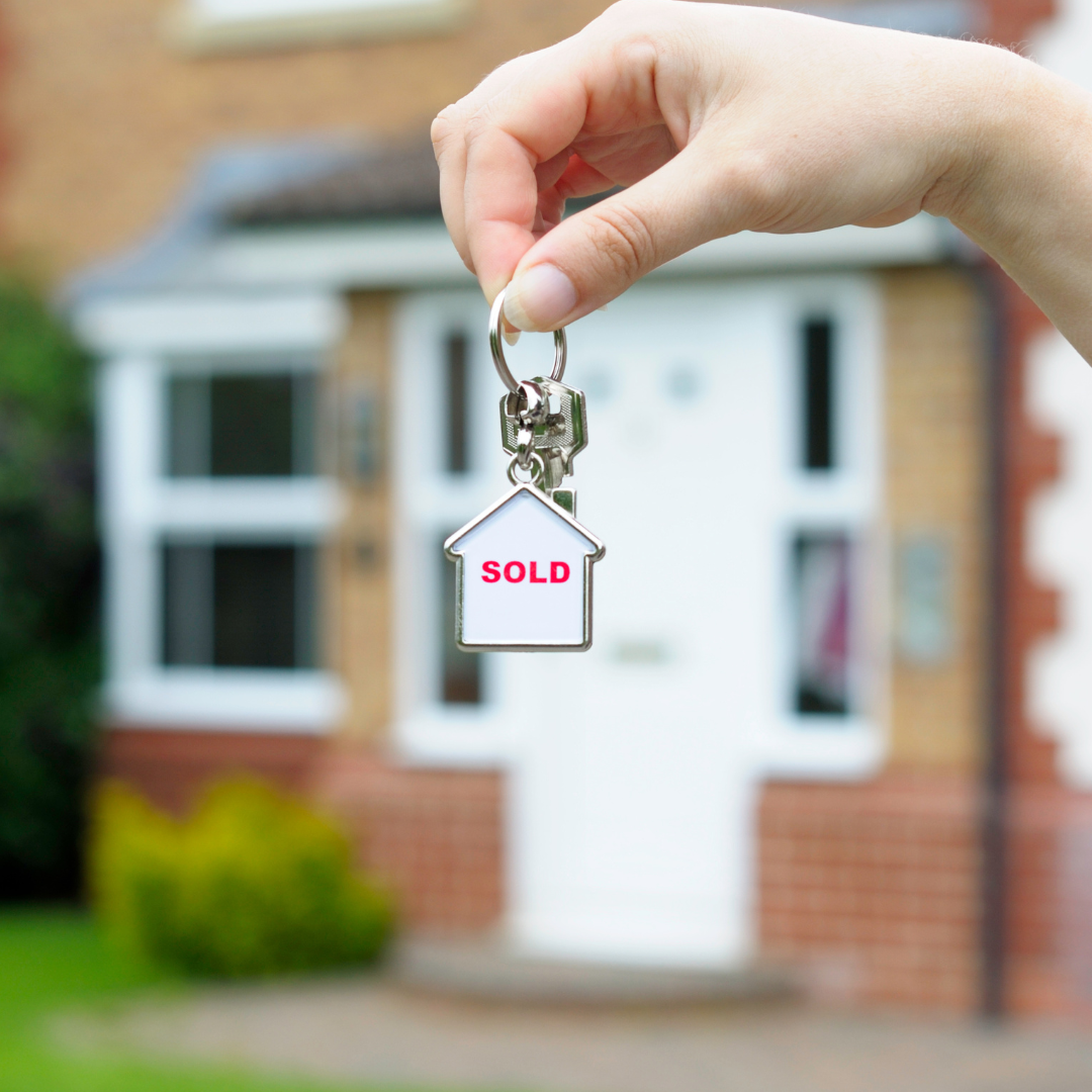 A photograph of a house with keys saying sold